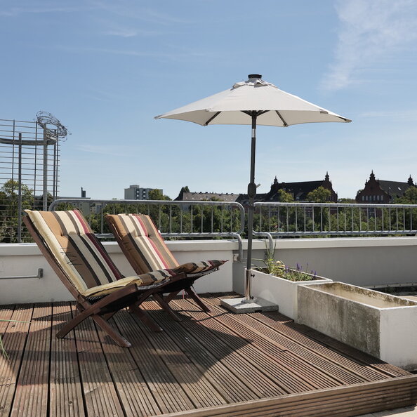 Dachterrasse mit Stühlen und Sonnenschirm